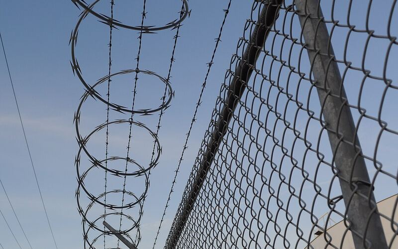 Concertina razor wire coil installed along the top of a perimeter fence