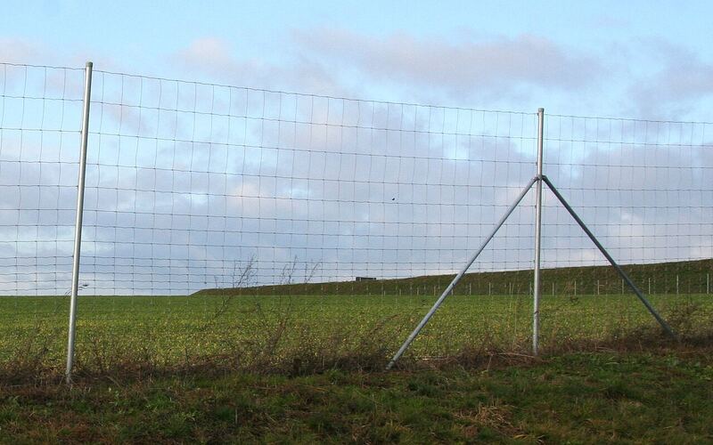 Grassland field fence with steel posts enclosing an open green field